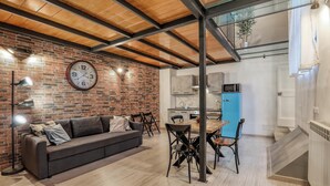 Un salon moderne avec un mur en briques, un plafond en bois, un canapé, une table à manger et des chaises.