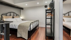 Une chambre à coucher moderne avec un lit, une table de chevet et un téléviseur fixé au mur.