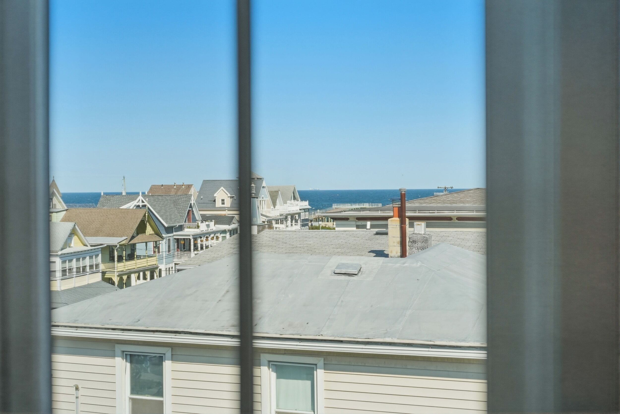 A coastal town with buildings, a clear sky, and the ocean in the background.