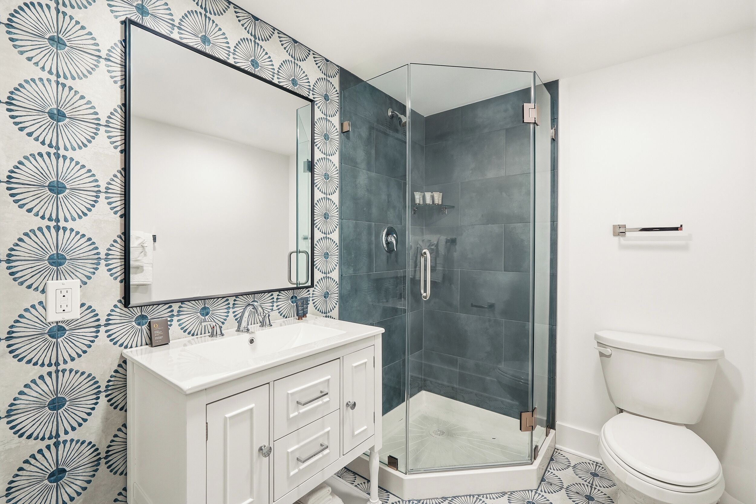 Une salle de bain avec une douche à parois de verre, un lavabo blanc et des toilettes.