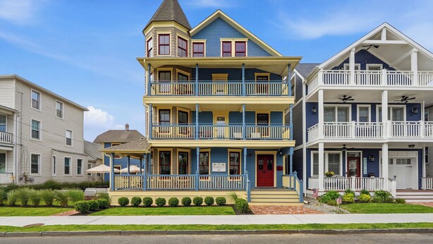A multi-story building with a balcony, a porch, and a sign indicating it is a hotel. - The Marilyn Inn (Ocean Grove)