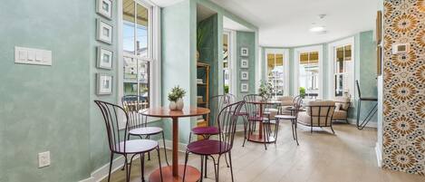A spacious dining area with round tables and chairs, large windows, and a view of the outside.