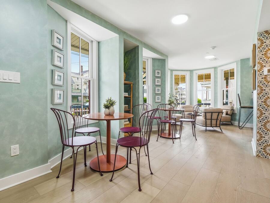 Un comedor amplio con mesas y sillas redondas, ventanas grandes y vistas al exterior.