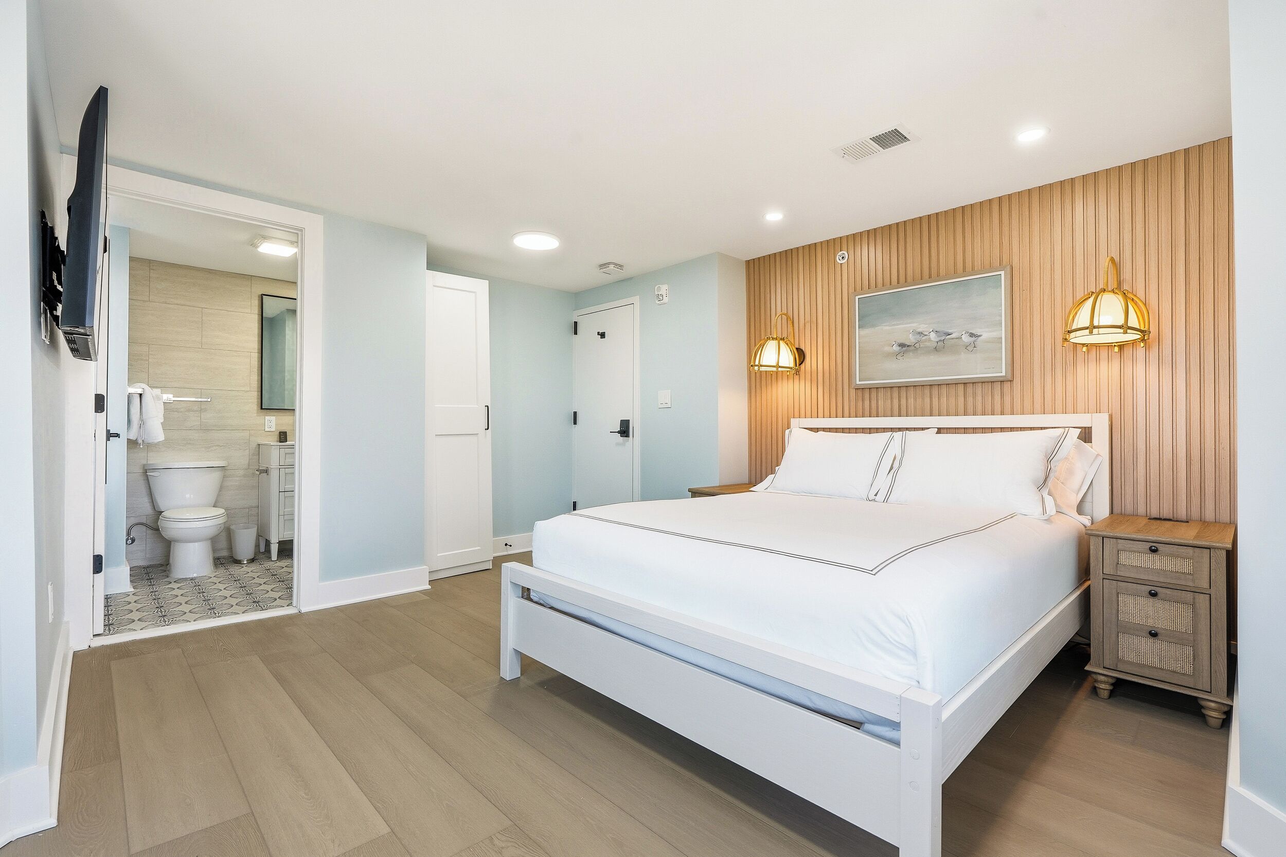 Une chambre à coucher avec un lit, une table de chevet et un luminaire fixé au mur.