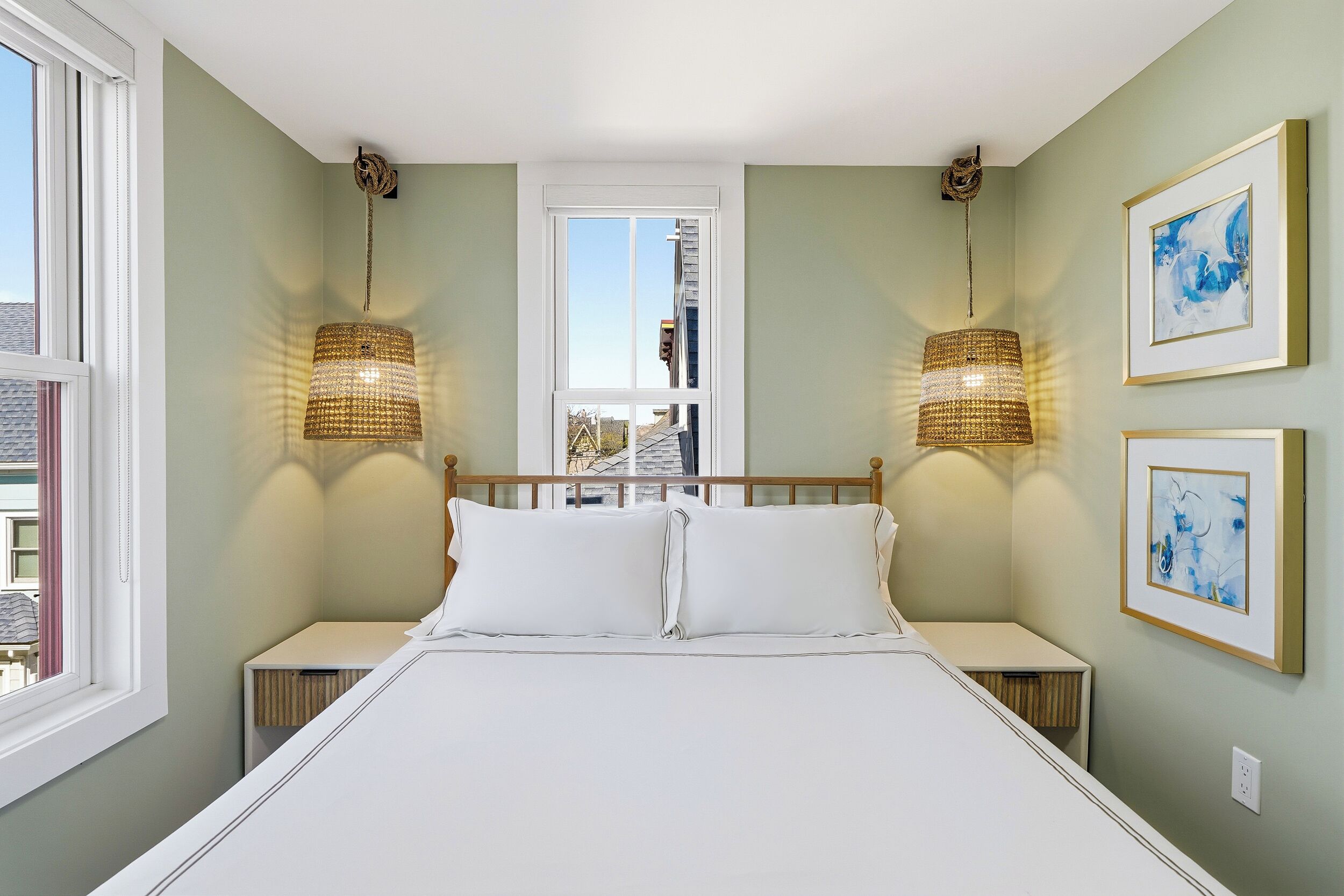 A bedroom with a bed, two bedside tables, a window, and two wall-mounted lamps.