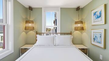 A bedroom with a bed, two bedside tables, a window, and two wall-mounted lamps.