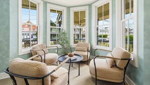 A corner room with four chairs, a table, and large windows. - The Marilyn Inn (Ocean Grove)