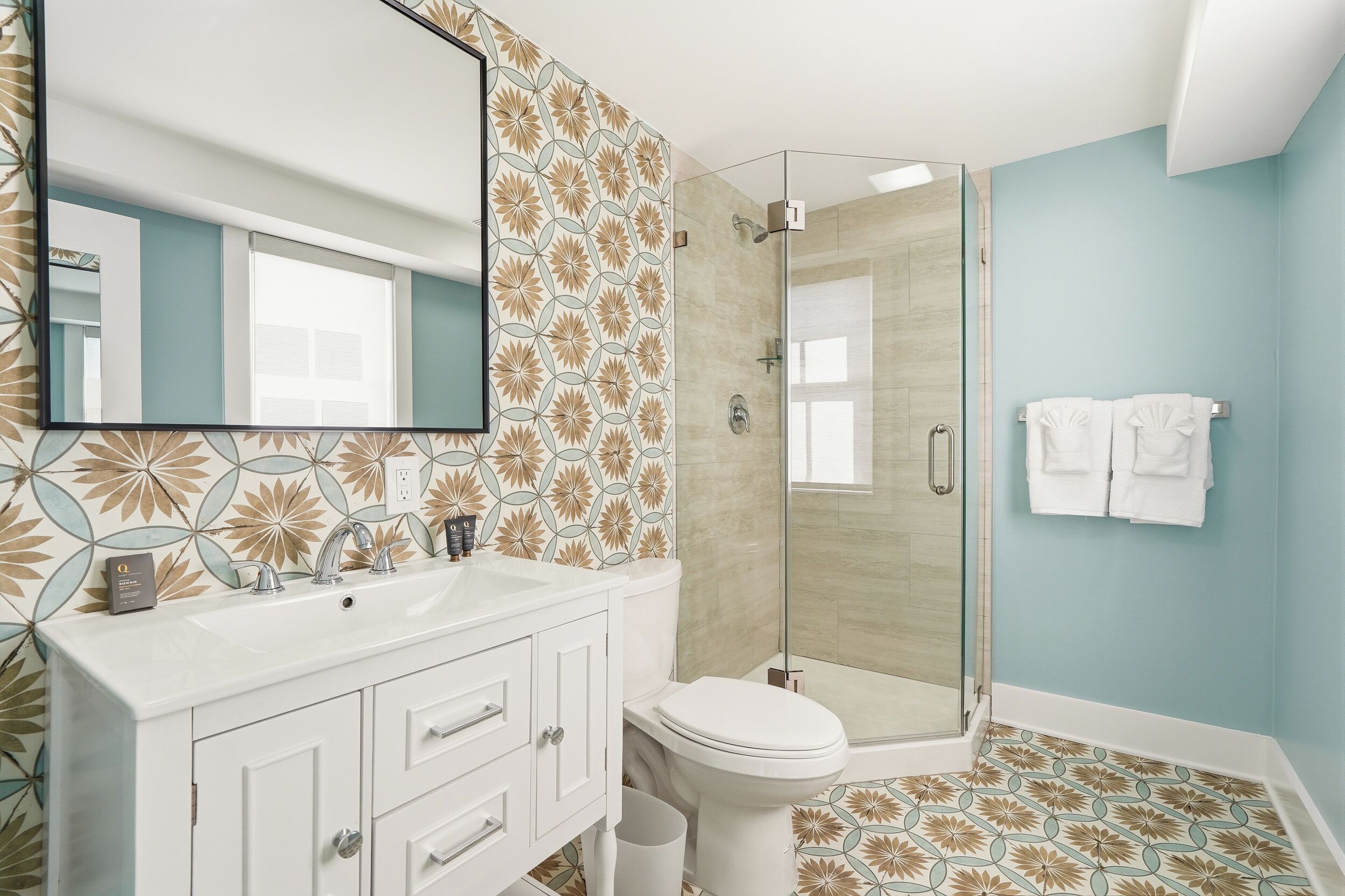 A bathroom with a shower, toilet, sink, and a mirror.