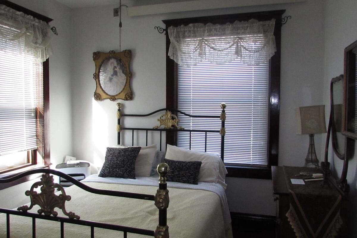 A bedroom with a bed, a bedside table, a lamp, and a mirror.