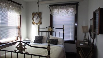 A bedroom with a bed, a bedside table, a lamp, and a mirror.