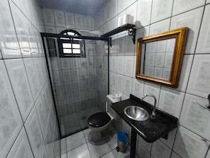 Ein Badezimmer mit Dusche, Toilette, Waschbecken und einem Spiegel mit goldener Rahmung.