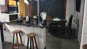 Eine kompakte Küche mit Mikrowelle, Kaffeemaschine, Wasserkocher und einem Essbereich mit Tisch und Stühlen.