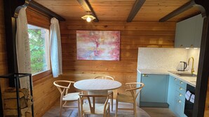 Interior acogedor de una cabaña con comedor de madera, cocina con armarios azul claro y un cuadro abstracto grande en la pared.
