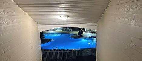 Un espace extérieur abrité, doté d’une piscine, de murs en bois et d’une rambarde en métal.