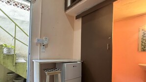 Een kleine keuken met een compacte koelkast, een kruk en een betegelde vloer.