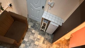 Een trap die uitkomt op een plateau met een bank en een kleine koelkast.