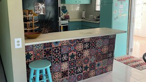Eine Küche mit türkisfarbenen Schränken, einer strukturierten Spritzschutzwand und einer Bar mit einem Barhocker.