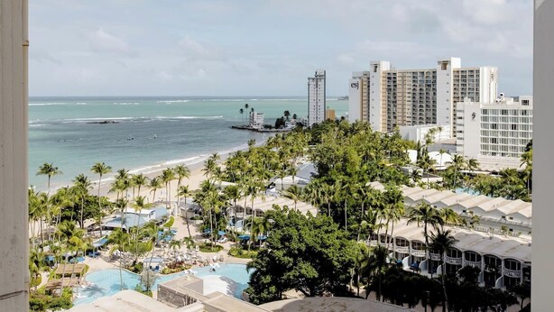 Ein Resort mit Pool, Palmen und Blick auf das Meer und hohe Gebäude.