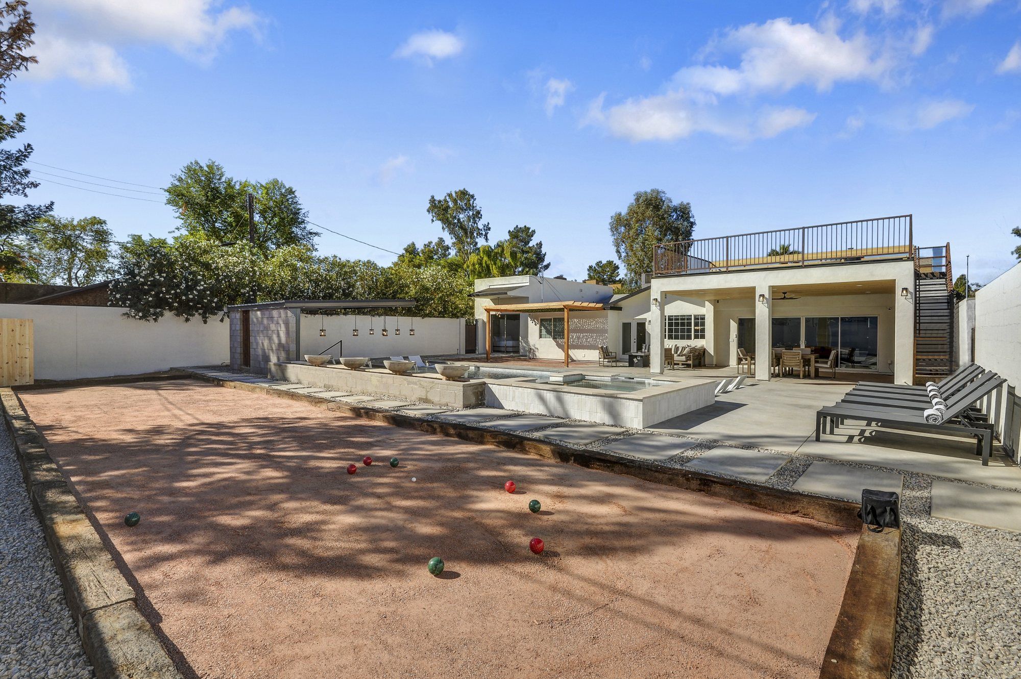 A modern outdoor patio area with a pool, seating, and a covered section.