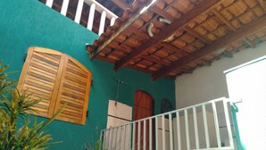 Un bâtiment à l’extérieur verdoyant, doté de volets en bois et d’une balustrade blanche.