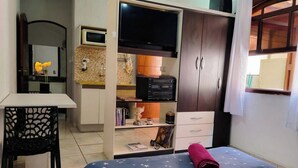 Une chambre à coucher comprenant un lit, un bureau, une armoire et un téléviseur.