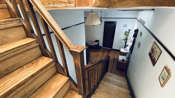 Una escalera de madera que lleva a una plataforma con una lámpara y una pequeña mesa.