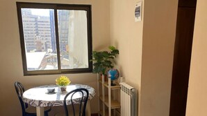 Un pequeño comedor con una mesa redonda, dos sillas, una planta en maceta, un globo terráqueo y un radiador.