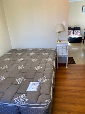 Un dormitorio con cama, mesita de noche con lámpara y cómoda pequeña.