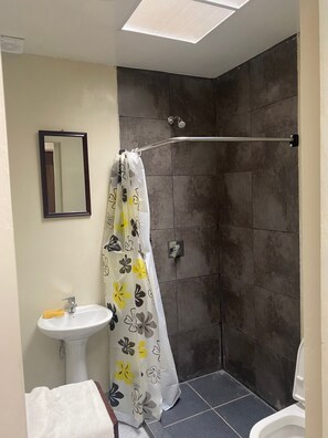 Un baño con ducha, lavamanos e inodoro.
