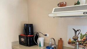Una cocina compacta con microondas integrado, cafetera y cocina a gas.