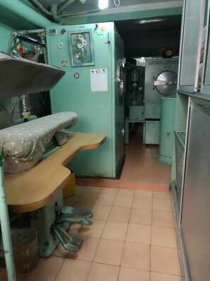 Cocina compacta con lavamanos, encimera y estufa. Hay varios utensilios de cocina y una planta en maceta sobre la encimera.