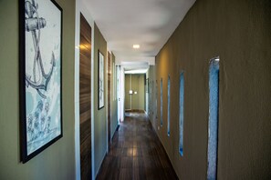 Un couloir doté de parquets en bois, d’œuvres d’art encadrées accrochées aux murs et d’un luminaire au plafond.