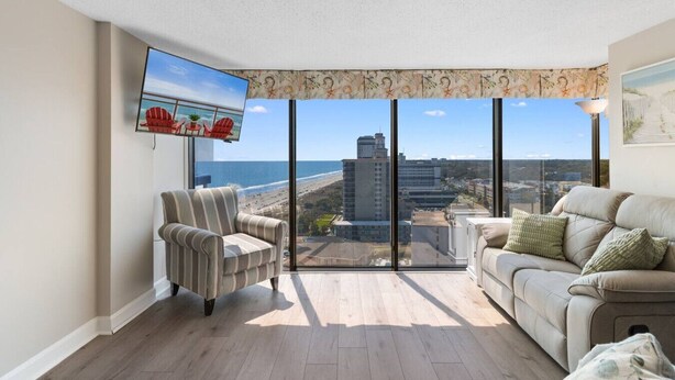 Un balcon spacieux avec vue sur la ville, une télévision à écran plat et un canapé.