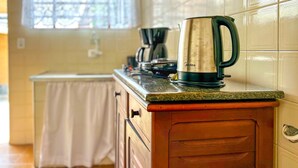 Uma cozinha com uma cafeteira de aço inoxidável no balcão, uma janela com vista e uma pia.