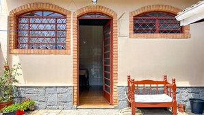 Um edifício com um banco de madeira, plantas em vasos e entrada com azulejos.
