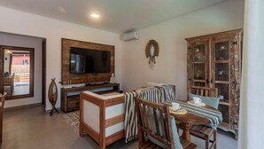 Una sala de estar con televisor, sofá, mesa de comedor y un aparador.