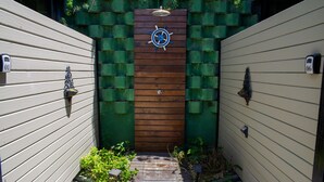 A wooden gate with a ship's wheel design, flanked by two walls with mailbox numbers 01 and 06. - Loft com Smart Lock e Ar Perto do Projeto Tamar (Ubatuba)