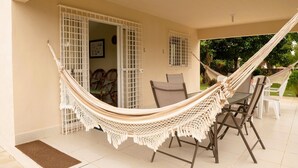 A hammock chair in a covered outdoor area with a dining table and chairs. - Casa com Piscina Churrasq Wi Fi pr Ximo ao mar (Ipojuca)