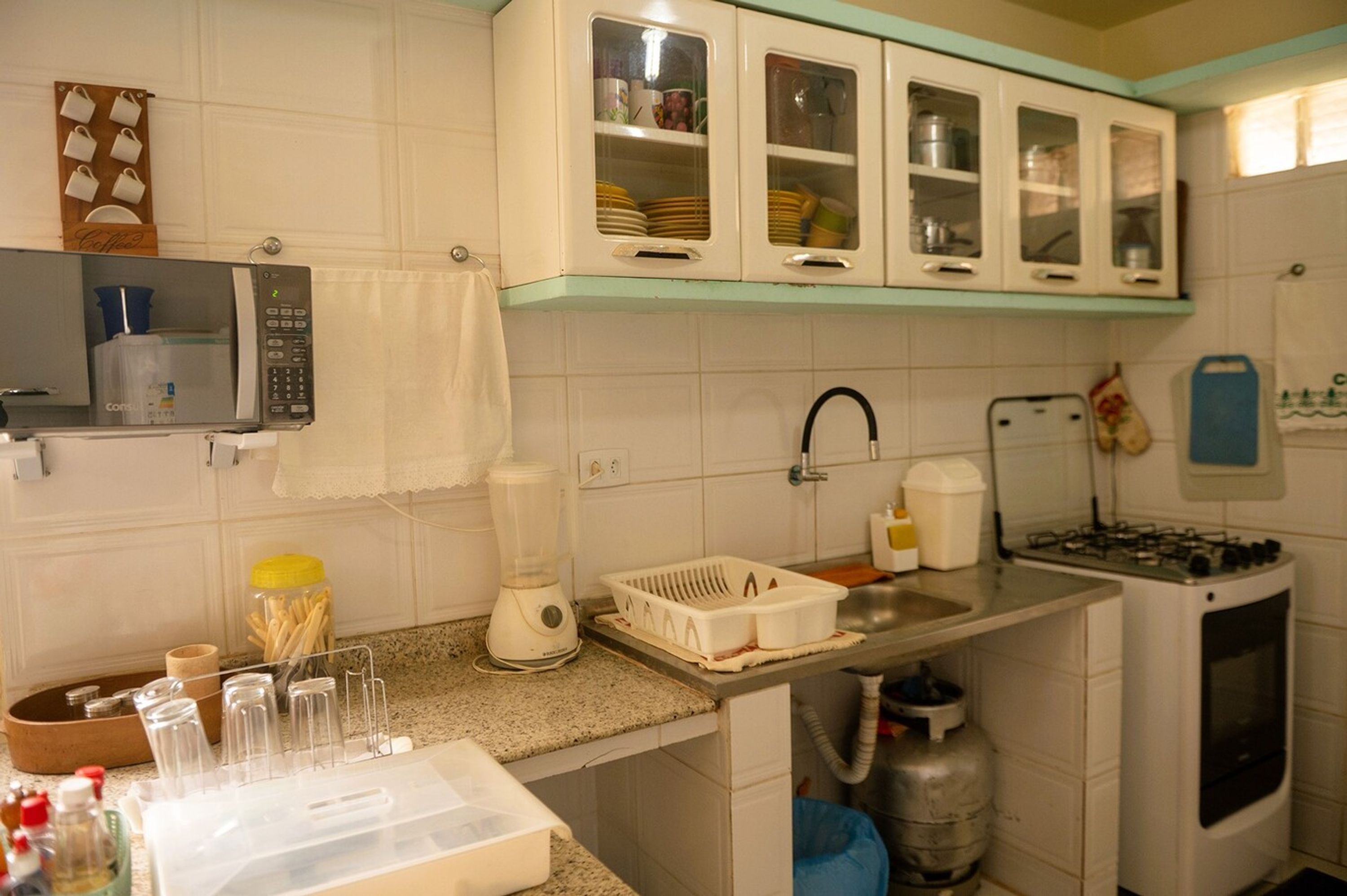 A kitchen with white cabinets, a microwave, a gas stove, and a sink.