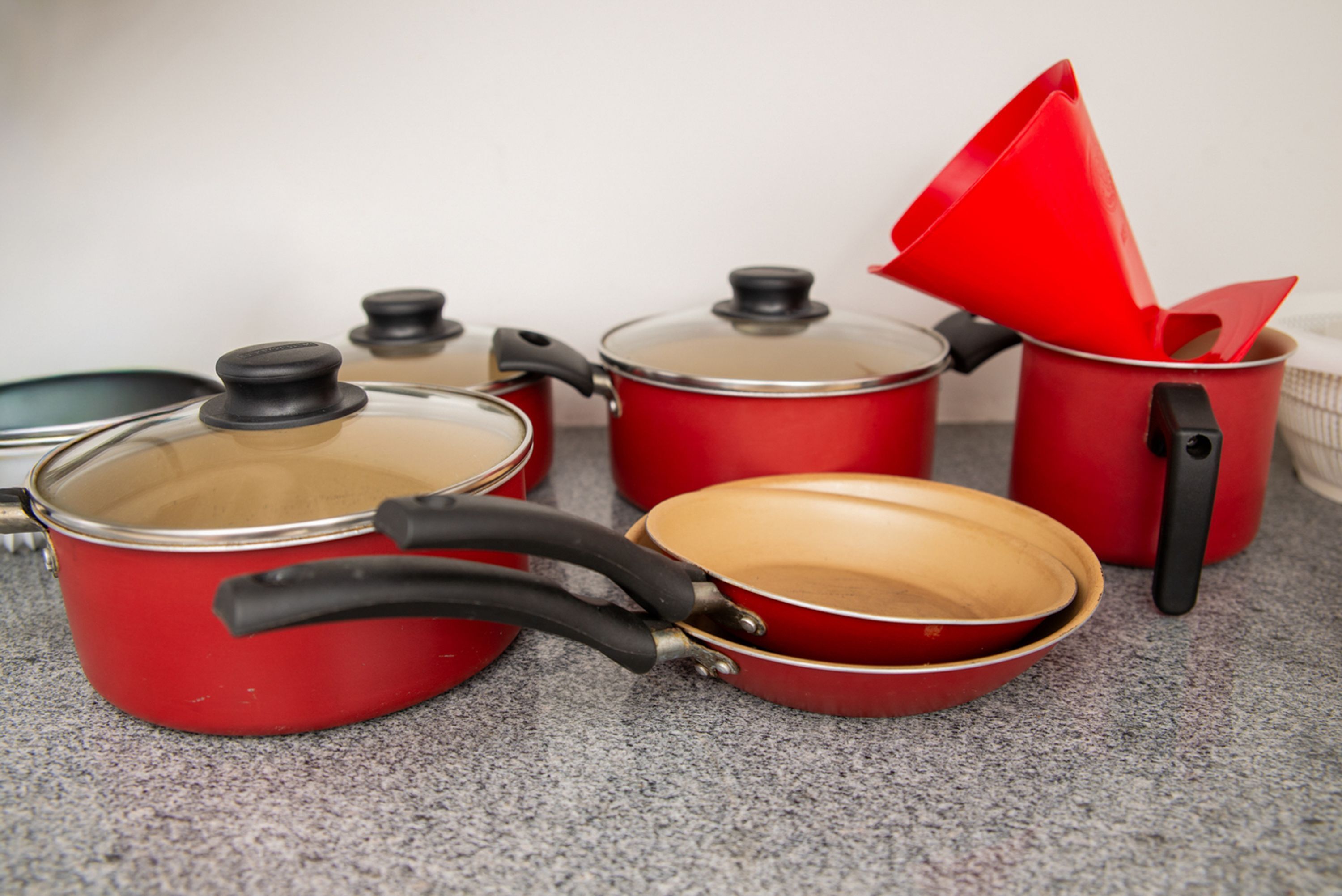 Juego de utensilios de cocina rojos con tapas y mangos sobre una encimera.