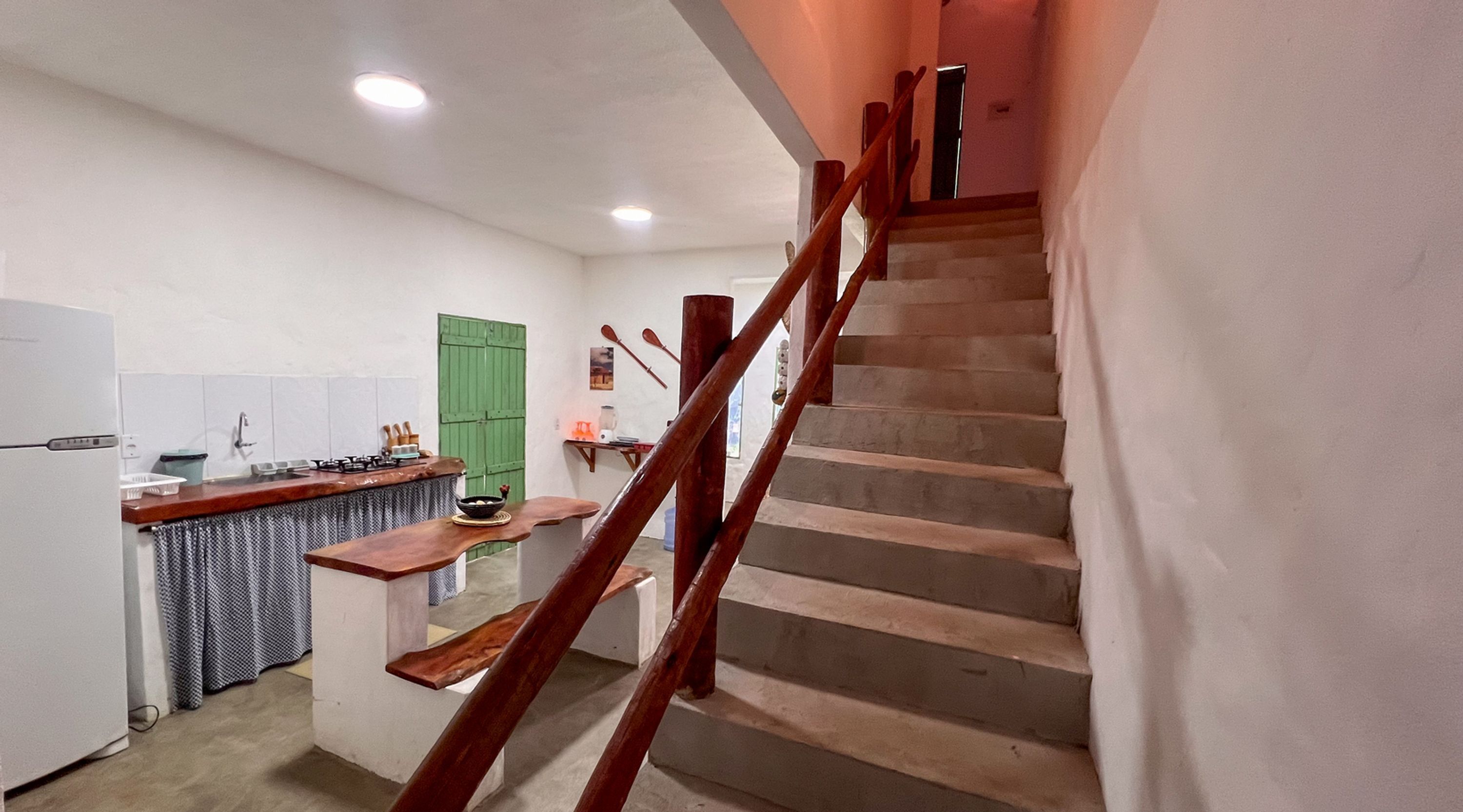 A kitchen with a wooden staircase leading to a landing.