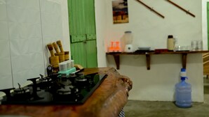 A kitchen with a gas stove, wooden utensils, a green door, and a wall-mounted paddle. - Casa Brisa das Guas Piscina e Churrasqueira (Porto de Pedras)