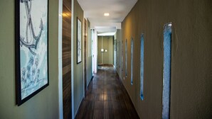 A hallway with wooden floors, framed artwork on the walls, and a light fixture on the ceiling. - Loft c Smart TV e Wi-fi pr x ao Aqu rio de Ubatuba (Ubatuba)