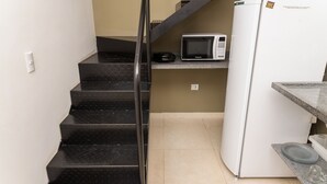 A kitchen with a microwave, refrigerator, and a staircase. - Loft com Wi-fi e Smart Lock pr x ao Projeto Tamar (Ubatuba)