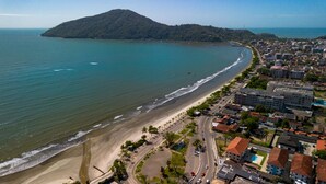 An aerial view of a coastal city with a beach, roads, and buildings. - Loft com Wi-fi e Smart Lock pr x ao Projeto Tamar (Ubatuba)
