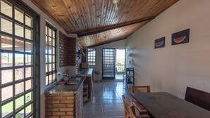 A spacious kitchen with a brick wall, large windows, and a wooden ceiling. - Casa de Campo com Piscina e Lareira em Bragan a (Braganca Paulista)