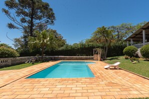 A rectangular swimming pool with a tiled deck, surrounded by a wooden fence and lush greenery. - Casa de Campo com Piscina e Lareira em Bragan a (Braganca Paulista)