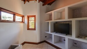 A room with a TV on a white shelf, a window, and a wooden ceiling. - Casa com Piscina Sal o de Jogos e Churrasqueira (Mairipora)
