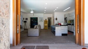 Un grand espace de vie comprenant un canapé, une table à manger avec des chaises, une cuisine équipée d’armoires et un ventilateur de plafond.