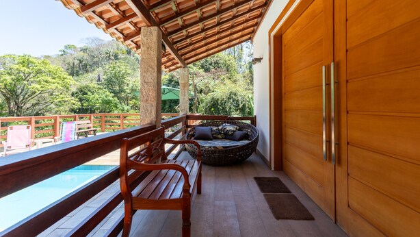 Une terrasse en bois avec une piscine, un banc et une grande porte en bois.